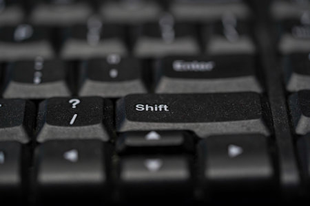 A close-up, high-angle macro photograph of a dusty black membrane keyboard featuring a shallow depth...