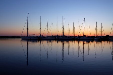 Sailing boats in marina at sunsetの写真素材