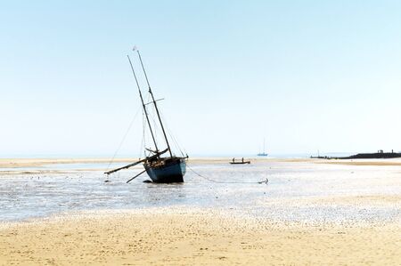 Fishing boat waiting on tidal shoreの写真素材