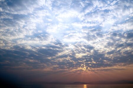 Sunrise over the sea and clouds in the skyの写真素材