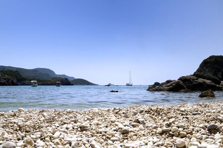 View of the bay with boats and beach pebbles の写真素材