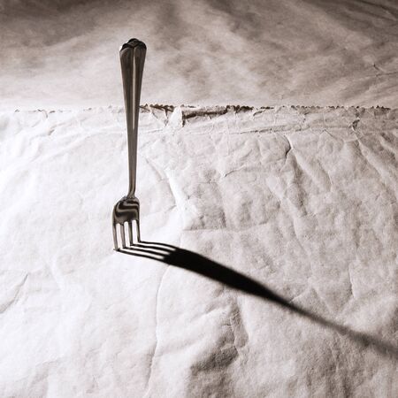 The metal fork stuck in the paper の写真素材