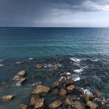 Blue sea, dark clouds and rain starting