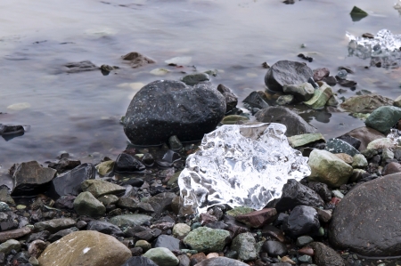 Black stone and white glacier ice on the shore of the lagoon