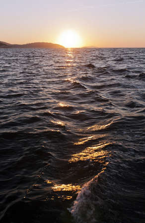 The sun going down over the mountain and seaの写真素材