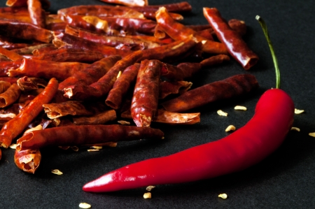 A closeup of fresh and dried red chili peppers  
