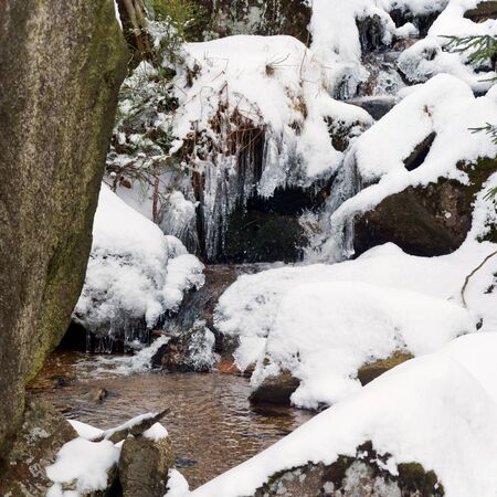 Winter landscape with a stream, stones and snowの写真素材