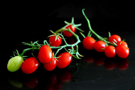 A bunch of oblong cherry tomatoes on the black backgroundの写真素材