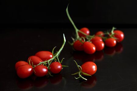 A bunch of oblong cherry tomatoes on the black backgroundの写真素材