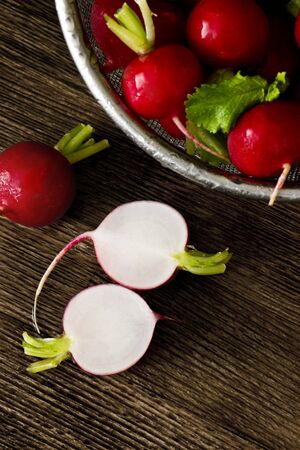 Several red radishes in a sieve a some radishes on a wooden board.の写真素材