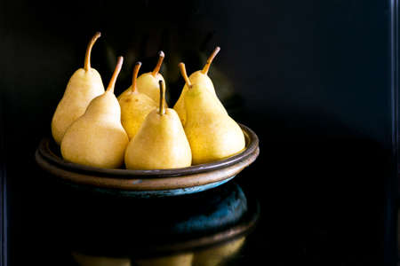Several yellow pears on a plate on a dark backgroundの写真素材