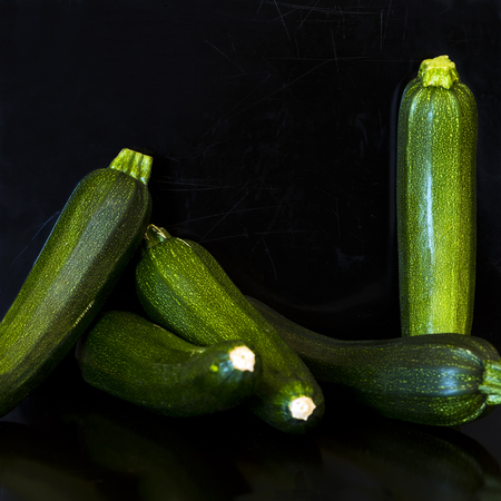 A group of green zucchini (zucchetti, courgettes) on a scratched black backgroundの写真素材