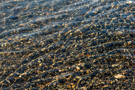 Ripples on a lake with clear water and pebbles at the bottom of the lake. Backgroundの写真素材