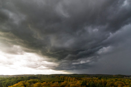 Dark storm clouds over colorful autumn forestの写真素材