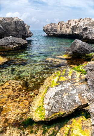 Wild beach with stony rocky shore and clear waterの写真素材