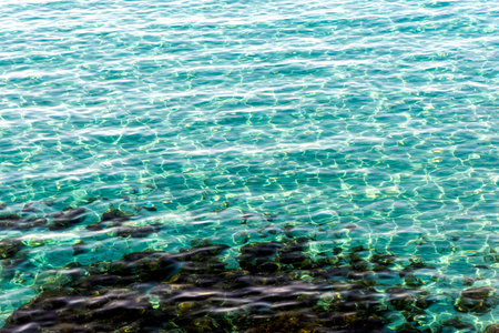 Light reflection on blue-green sea surface. A view of the sandy bottom below the surface. Abstract texture, background.の写真素材