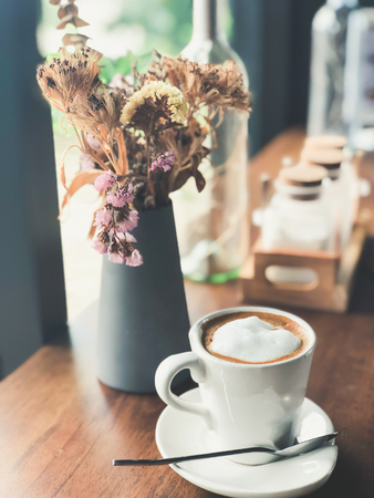 hot cappuccino coffee in white cup on wood table with flower at cafe'の写真素材