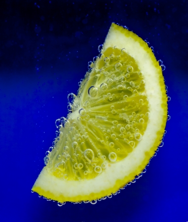 Lemon with bubbles on the blue backgroundの写真素材