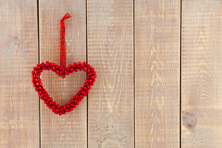 Valentine's day card with red heart hanging over wooden backgroundの写真素材
