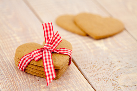 gingerbread hearts tied with ribbon on wooden planksの写真素材