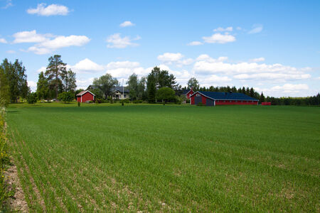 The view to the red farmhouse in rural Finlandの写真素材