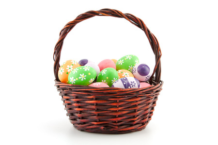 colored Easter eggs in a basket on a white backgroundの写真素材