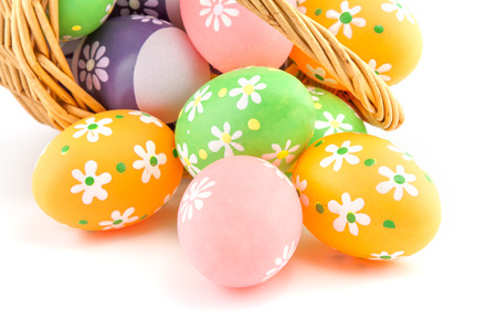 colored Easter eggs in a basket on a white backgroundの写真素材