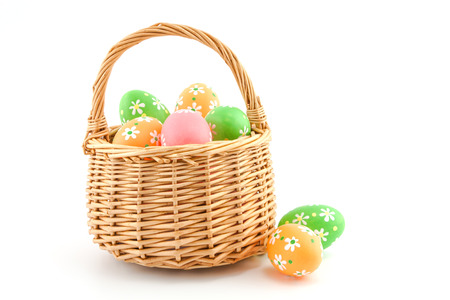 colored Easter eggs in a basket on a white backgroundの写真素材