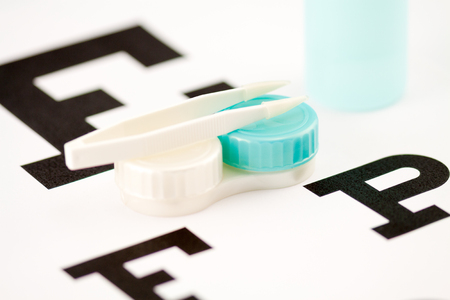 Contact lens case with tweezers on eye test chartの写真素材
