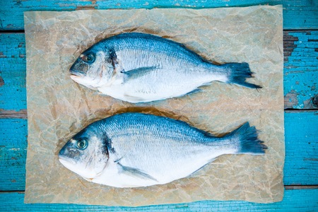 two raw dorado fishes  on a rustic backgroundの写真素材