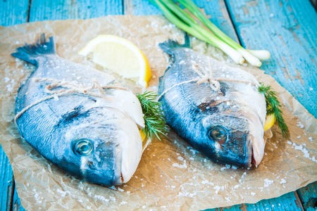 two raw dorado fishes with lemon, green onions on a rustic backgroundの写真素材