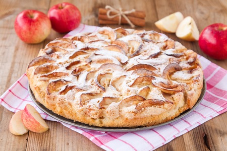apple pie on a wooden background with cinnamon and red applesの写真素材