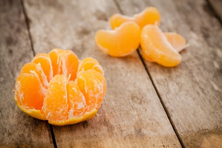 fresh organic mandarins and peeled slices on a rustic wooden backgroundの写真素材