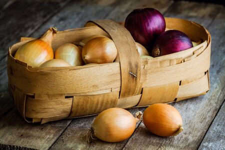 Fresh organic onions in a basket on a wooden backgroundの写真素材