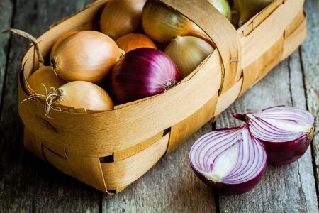 Fresh organic onions in a basket on a wooden backgroundの写真素材