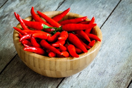 red hot chili peppers in a bowl on wooden rustic backgroundの写真素材