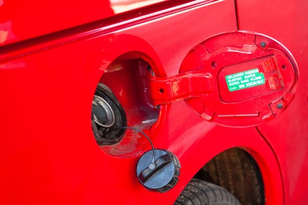Person refueling a red car at gas station