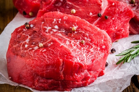 raw steaks with rosemary, sea salt and pepper on wooden backgroundの写真素材