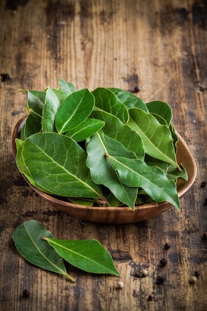 Fresh bay leaves in a wooden bowl on a rustic wooden backgroundの写真素材