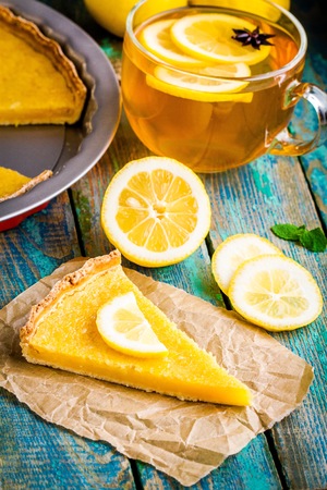 piece of lemon tart with cup of tea on rustic blue tableの写真素材