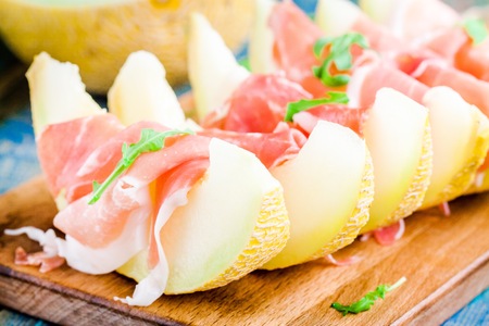fresh melon with thin slices of prosciutto and arugula leavesの写真素材