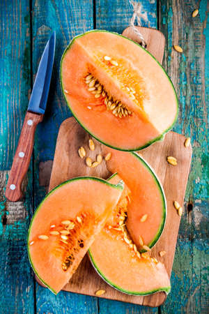 sliced ripe melon on a cutting board on rustic wooden background