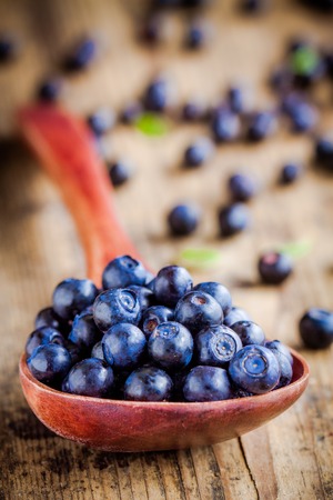 Fresh organic blueberries in a spoon on wooden tableの写真素材