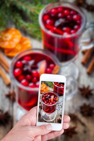 Hands taking photo mulled wine on wooden table with smartphoneの写真素材
