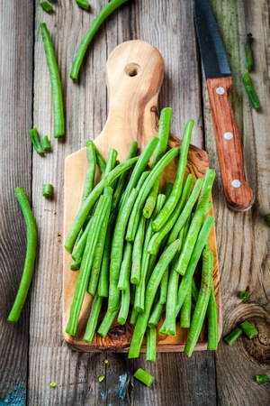 pods of fresh organic green beans in a wooden cuttin board on a rustic tableの写真素材
