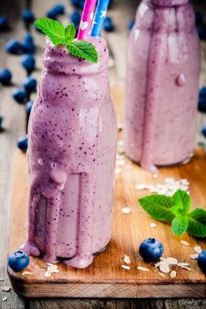 Blueberry smoothie in glass bottles closeup on rustic tableの写真素材