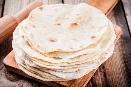 Stack of homemade wheat tortillas on wooden table