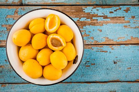 Fresh ripe organic apricots in bowl on a rustic background above viewの写真素材