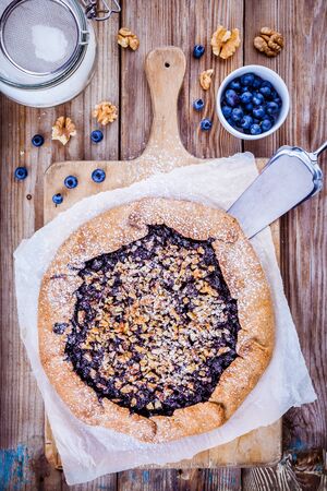 homemade galette with blueberries and walnuts on wooden rustic tableの写真素材