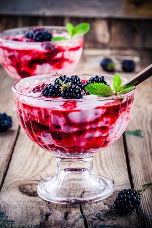 healthy dessert: yogurt parfait with blackberry and mint in glass on rustic wooden tableの写真素材